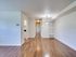 A bright unfurnished open hallway featuring polished hardwood floors and contemporary lighting for a stylish and inviting atmosphere.