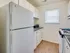 A welcoming kitchen featuring sleek white appliances, abundant natural light, and beautiful wood flooring for a bright and modern feel.