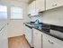 A bright compact kitchen featuring white cabinets, a stove, and stylish wooden flooring for a beautiful modern space.