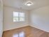 A spacious empty bedroom with hardwood flooring, abundant natural lighting, a large window, and a closet to create a bright, airy atmosphere.