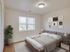 A bright and welcoming bedroom featuring modern neutral decor, a large window for natural light, and a comfortable cozy bed.