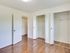 A bright bedroom with wooden floors, featuring multiple built-in closets and sleek white doors for a clean, organized look.