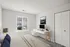 A bright bedroom with a cozy bed, plenty of natural light from a window, and a compact work desk with a minimalist chair, offering a serene and functional space.