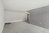 A bright and airy living space featuring a soft carpet and clean, minimalist gray and white walls.