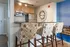 Elegant kitchen with stylish bar stools, stainless steel appliances, and decorative wall clock.
