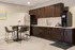 Sophisticated kitchen with dark wood cabinets, a stainless steel refrigerator, and a stylish dining area with modern chairs.