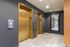 Sleek elevator lobby with gold doors, modern wall paneling, and a large mirror.