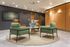 Inviting lounge with green and brown modern chairs around a stylish round table, complemented by contemporary decor.