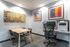 Modern office area with a minimalist desk, ergonomic chair, printer, and abstract art on walls.