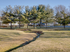 A peaceful park view with lush trees and a picturesque creek, all beneath a clear blue sky, offering a serene natural setting.