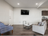A contemporary living room with a comfortable seating area, stylish wall-mounted TV, and an open kitchen layout, ideal for modern living.