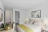 A brightly furnished bedroom featuring a comfortable bed, modern art, and a desk area, ideal for relaxation.