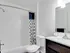A chic bathroom with a modern vanity, whilte tile accents, and an elegant shower curtain.