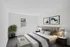 An elegant bedroom featuring a plush bed, modern decor, and vibrant artwork.