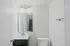 A minimalist bathroom featuring modern fixtures, a sleek vanity, and a large mirror.