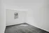 A bright and airy bedroom with spacious layout, soft gray carpet, and a single window offering a serene view.