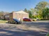 The charming exterior of apartment complex Catons Villas North, featuring a large parking area beneath a bright, clear blue sky.