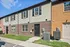 The charming exterior of a townhouse at Catons Villas North featuring a brick facade and a beautifully maintained front entrance.