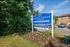 A vibrant blue sign for Catons Villas North Townhome Community, located next to a gravel path with attractive landscaping.