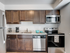 A modern kitchen featuring dark wood cabinets, stainless steel appliances, blue accents, and a stylish marble countertop.