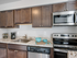 A modern kitchen with sleek granite countertops, stainless steel appliances, and elegant brown wooden cabinets.