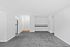 Spacious white room with soft gray carpet and modern white cabinets, located in The Greenbriar Apartments.