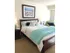 A modern, furnished bedroom featuring a bed and a painting at the Reserve at Sawmill.