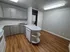 Modern kitchen with sleek gray cabinets, hardwood floors, and integrated laundry area, perfect for stylish urban living.