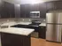 Modern kitchen with elegant dark wood cabinets, sleek stainless steel appliances, and a spacious marble countertop.