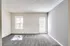 Spacious empty room in Perkins Place Apartments with gray carpet and white walls, ideal for personalizing your space.