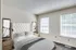 Cozy bedroom in Perkins Place Apartments featuring a bed, dresser, and a bright window letting in natural light.