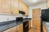 Stylish kitchen with wood cabinets and black appliances, located in the Greens at Schumaker Pond apartments.