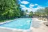Tranquil pool area at Quiet Waters Landing, part of the Woodlands Apartments, framed by lush trees.