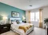 Inviting bedroom with elegant decor, featuring a cozy bed, teal accent wall, and ample natural light from a large window at Union Flats.
