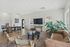 Bright, modern living area featuring a cozy leather sofa, stylish armchairs, a polished wooden dining table, and a large flat-screen TV, accented by lush plants and natural light at Emerson Flats.