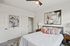 Elegant bedroom featuring stylish decor, abstract paintings, cozy bed with plush pillows, and a modern ceiling fan at Emerson Flats.