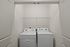 Modern laundry nook featuring high-efficiency washer and dryer with sleek shelving above, perfect for streamlined living at Emerson Flats.