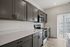 Elegant modern kitchen with sleek gray cabinets, stainless steel appliances, and ample natural light, perfect for culinary creativity at Emerson Flats.