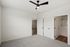 Bright and modern empty room with cozy carpet flooring, ceiling fan, and sleek doors leading to a bathroom and hallway at Emerson Flats.