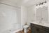 Modern bathroom featuring a sleek glass light fixture, elegant vanity with a large mirror, and a spacious walk-in shower at Emerson Flats.