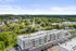 Aerial view of a modern apartment complex surrounded by lush greenery and a charming suburban landscape, showcasing convenient urban living in a serene environment at Emerson Flats.