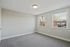 Bright, airy room with plush carpeting and large, sunlit windows offering a charming neighborhood view.