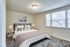 Cozy bedroom with plush carpet, stylish bed, and large windows offering natural light.
