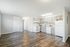 Bright, modern kitchen and open-concept living space with elegant wood flooring and ample cabinetry.