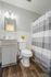 Modern bathroom with elegant vanity, cozy lighting, and stylish striped shower curtain on hardwood flooring.