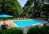 Inviting outdoor pool area surrounded by lush greenery, featuring lounge chairs and blue umbrellas for relaxation.