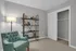 Chic apartment room showcasing a cozy armchair, stylish shelving, and ample closet space, perfect for modern living.