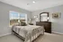 Bright and elegant bedroom with cozy bedding, stylish metal bed frame, and modern furnishings, bathed in natural light.