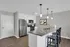 Modern kitchen with granite countertops, stylish pendant lighting, and sleek stainless steel appliances. Open-plan design enhances space and functionality.