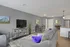Modern living room with chic gray walls, cozy gray sofa accented by vibrant purple pillows, stylish furniture, and a sleek open-concept kitchen.